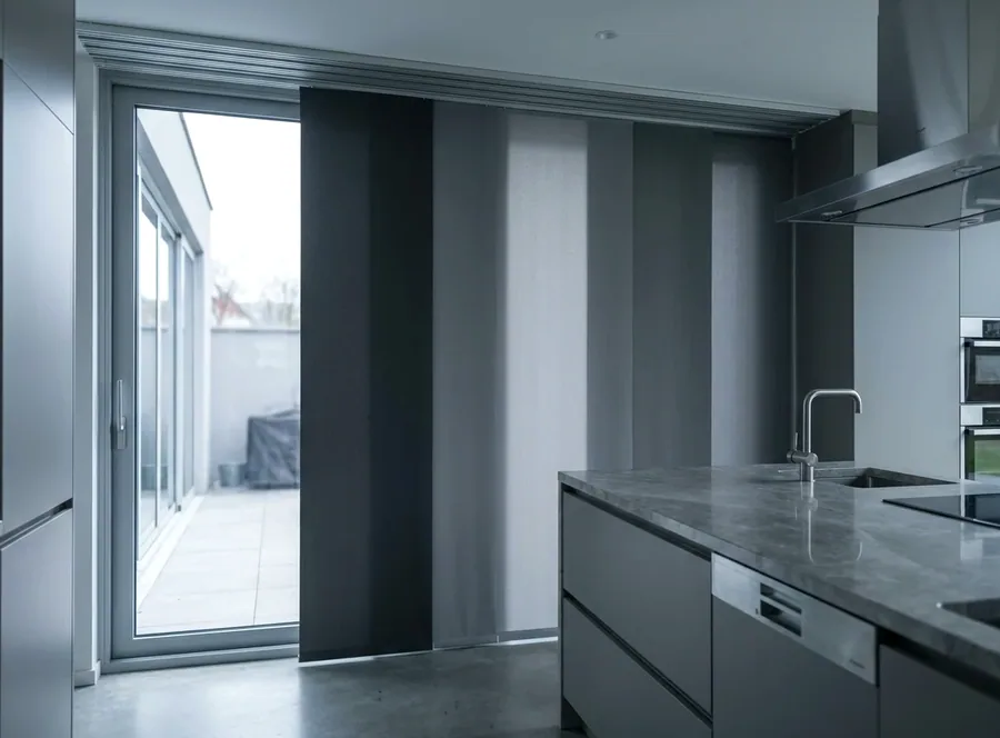 Panel blinds sliding on a multi-channel ceiling track across a wide stack door